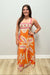 woman wearing orange dress with pink detailing on plain background