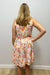Woman wearing a floral dress against a plain wall.