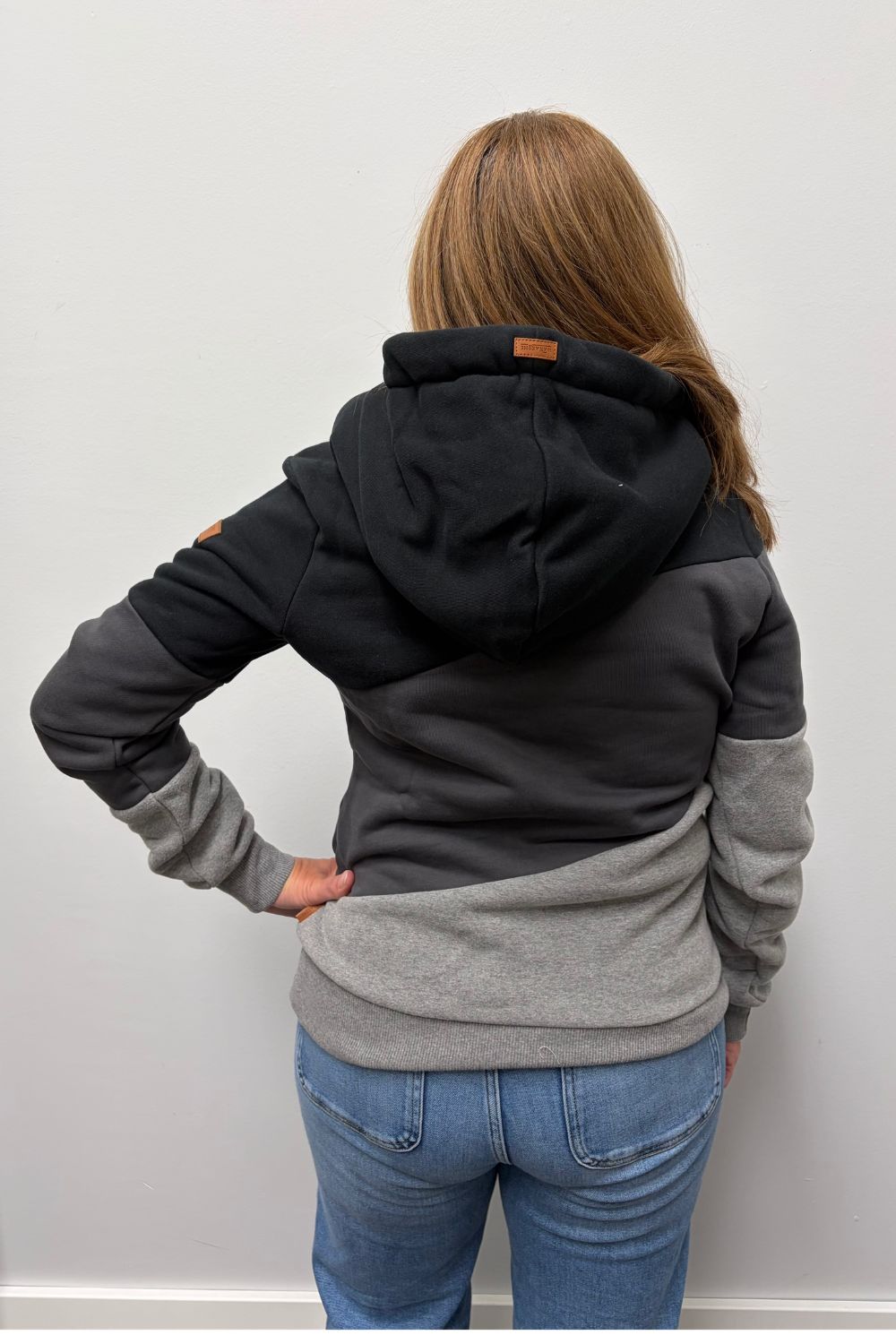 Woman wearing Wanakome Selene Hoodie In Black Carbon Mix on a plain white background.