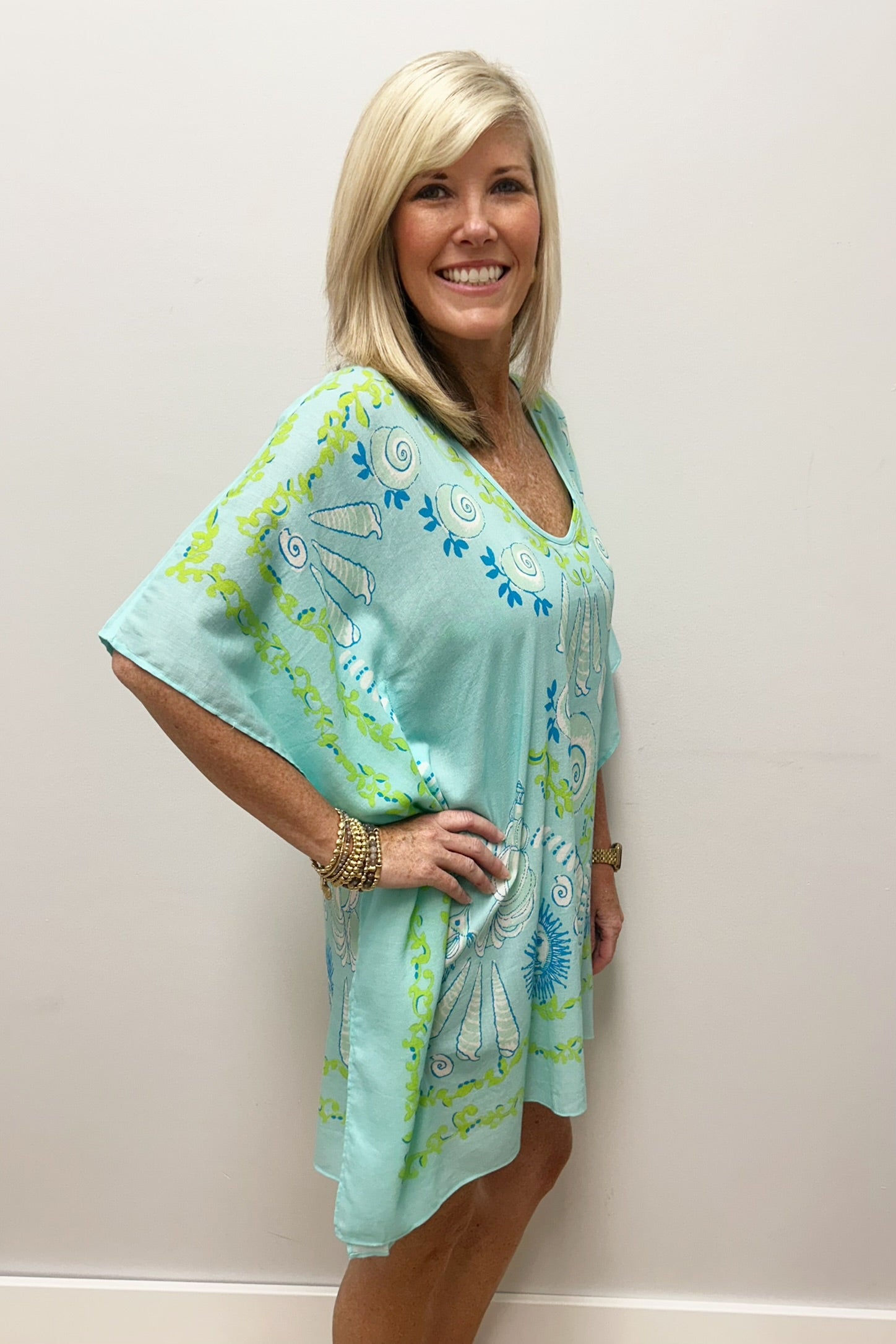 Woman wearing light blue beach cover up with white, blue and green nautical pattern