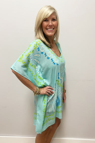 Woman wearing light blue beach cover up with white, blue and green nautical pattern