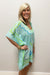 Woman wearing light blue beach cover up with white, blue and green nautical pattern