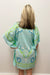 Woman wearing light blue beach cover up with white, blue and green nautical pattern