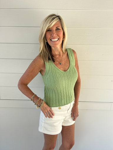 woman wearing green knitted tank against white background
