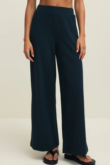 Person wearing navy blue wide-leg pants on a plain background