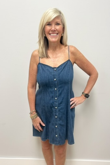 Woman wearing a blue denim dress against a plain background