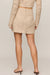woman wearing tan embroidered skirt on a white background