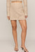 woman wearing tan embroidered skirt on a white background