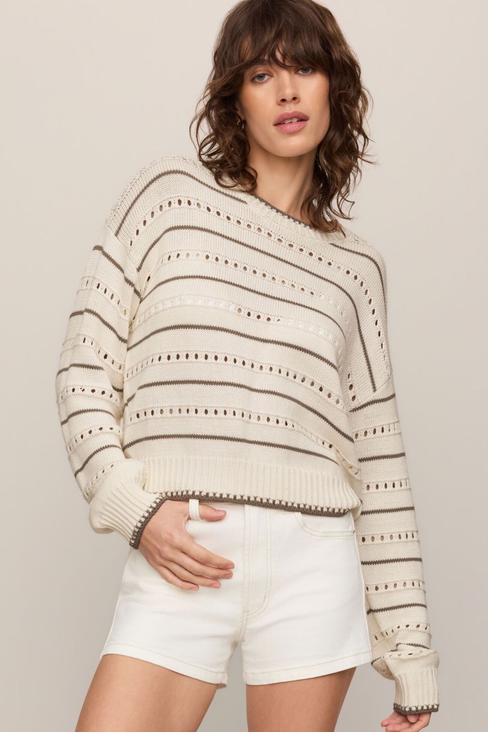 woman wearing tan striped sweater on a white background