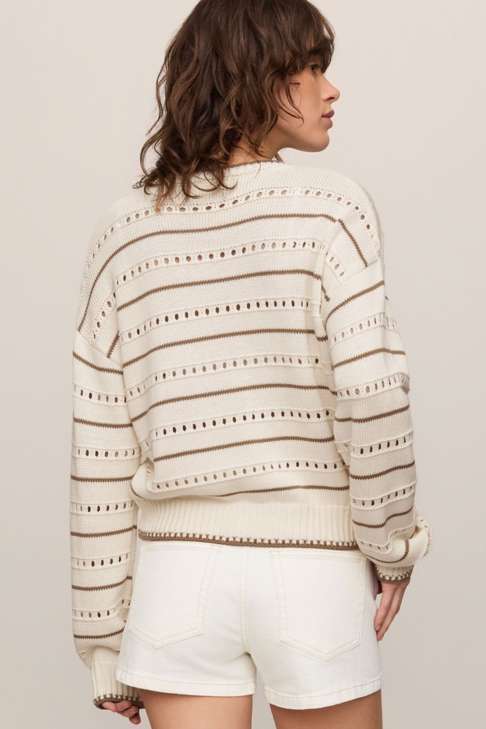 woman wearing tan striped sweater on a white background