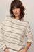 woman wearing tan striped sweater on a white background