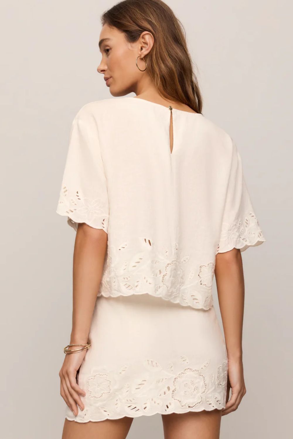 woman wearing embroidered white top on a white background 