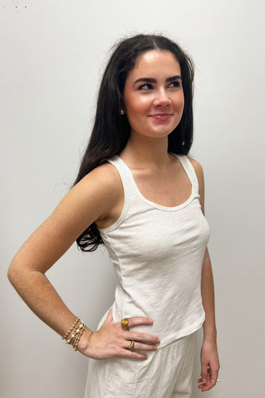 Woman wearing white tank top against gray background