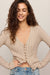 woman wearing tan button sweater with white background