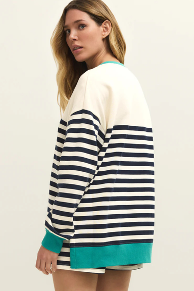 Woman wearing a navy and white striped sweater with teal trim on a plain background