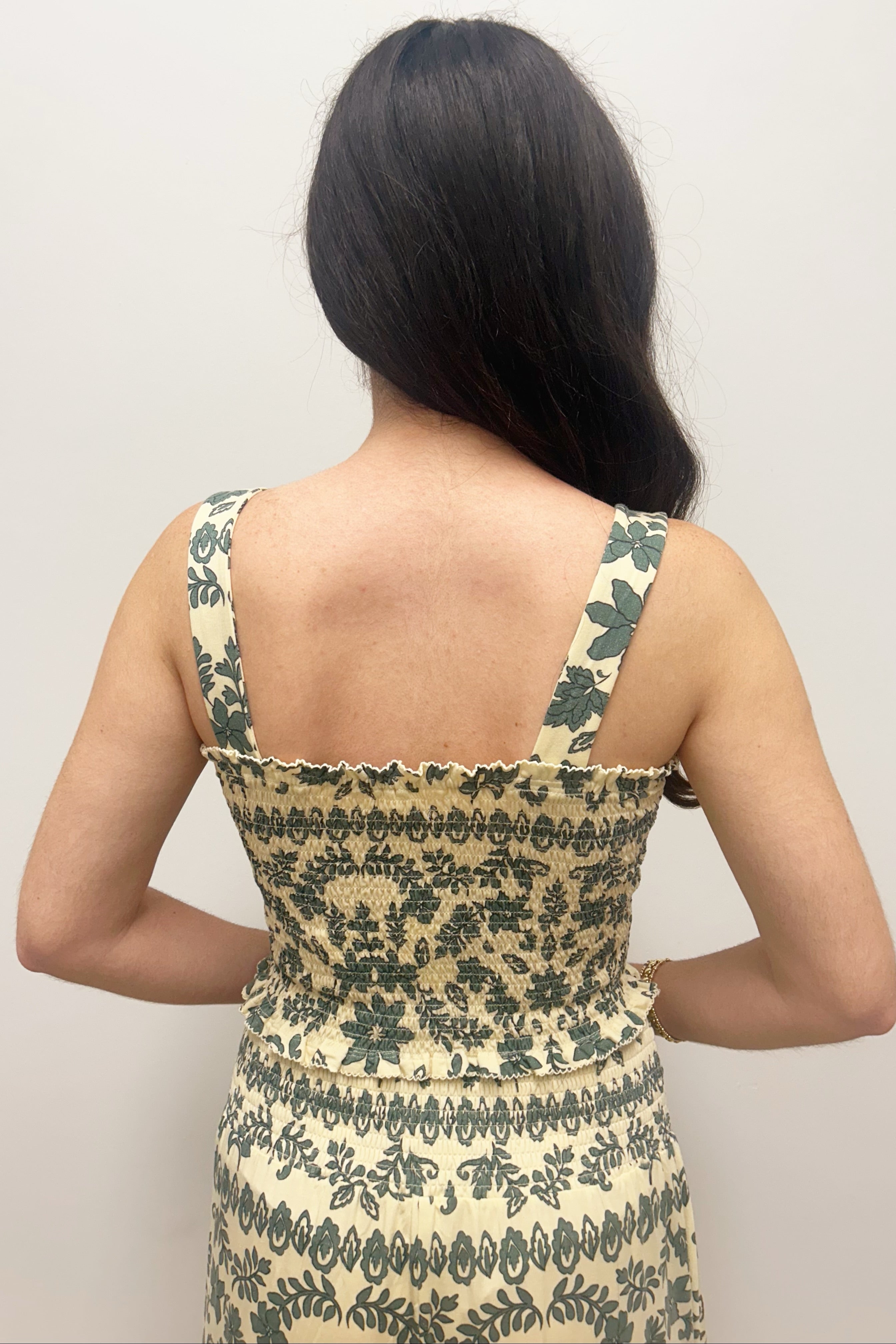 Woman wearing cream tank top with green floral detail