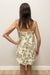 woman in cream dress with green palm tree detail
