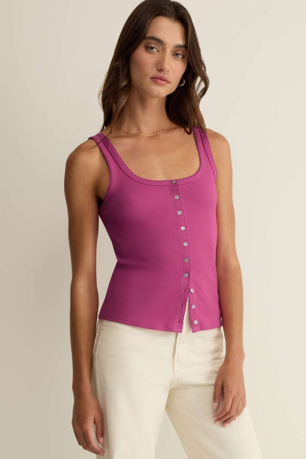Woman wearing a pink tank top with buttons on a beige background