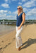 Woman standing on a sandy beach with a blue sky and clouds in the background
