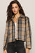 Woman modeling a plaid jacket on a plain white background