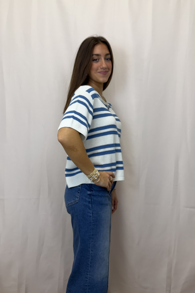 Woman wearing a blue and white striped shirt and blue jeans against a plain background