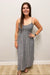 Woman wearing a gray striped dress standing against a plain wall.