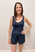 Woman wearing a navy tank top and shorts against a plain background