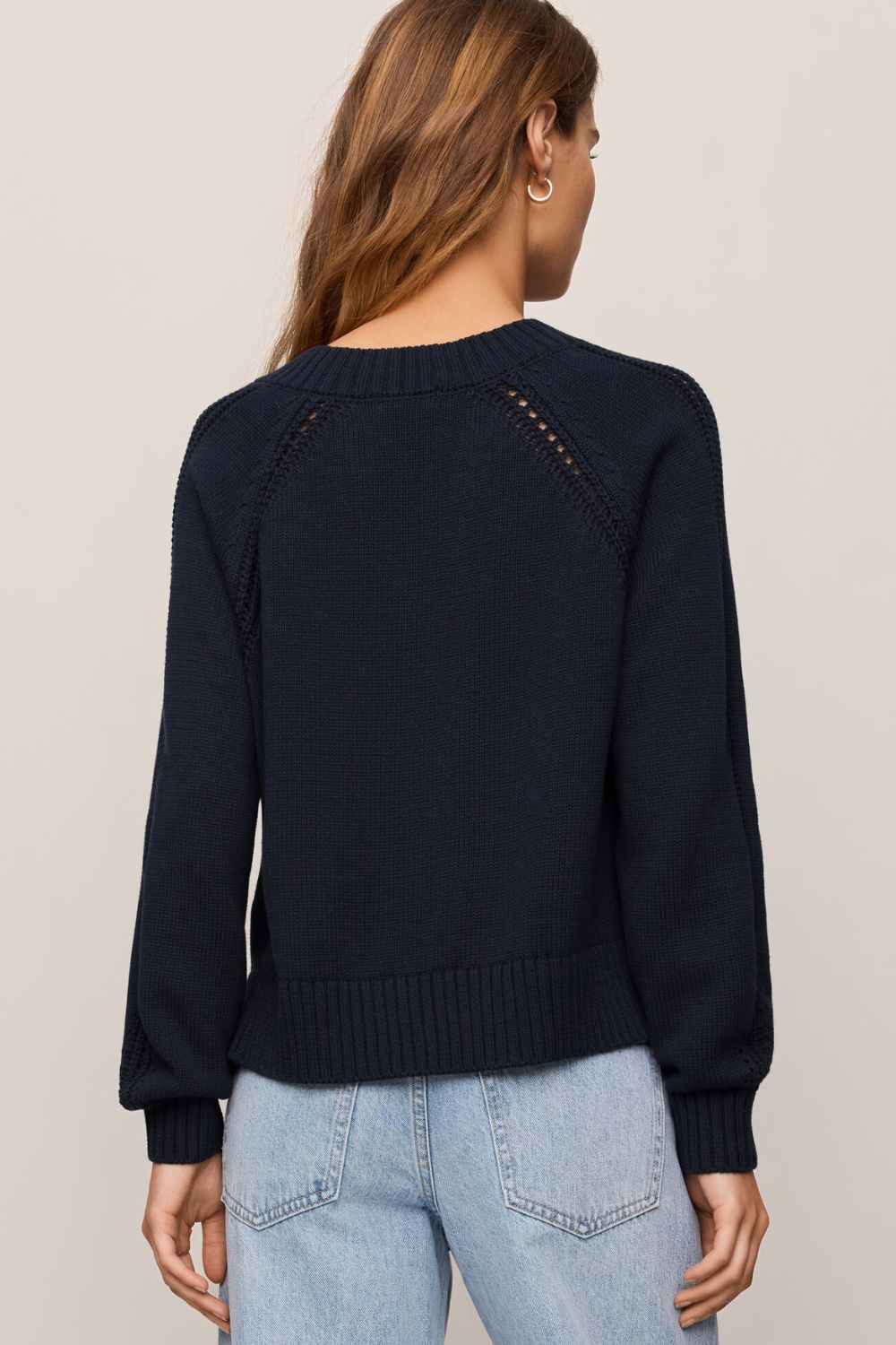 woman wearing navy sweater on a white background