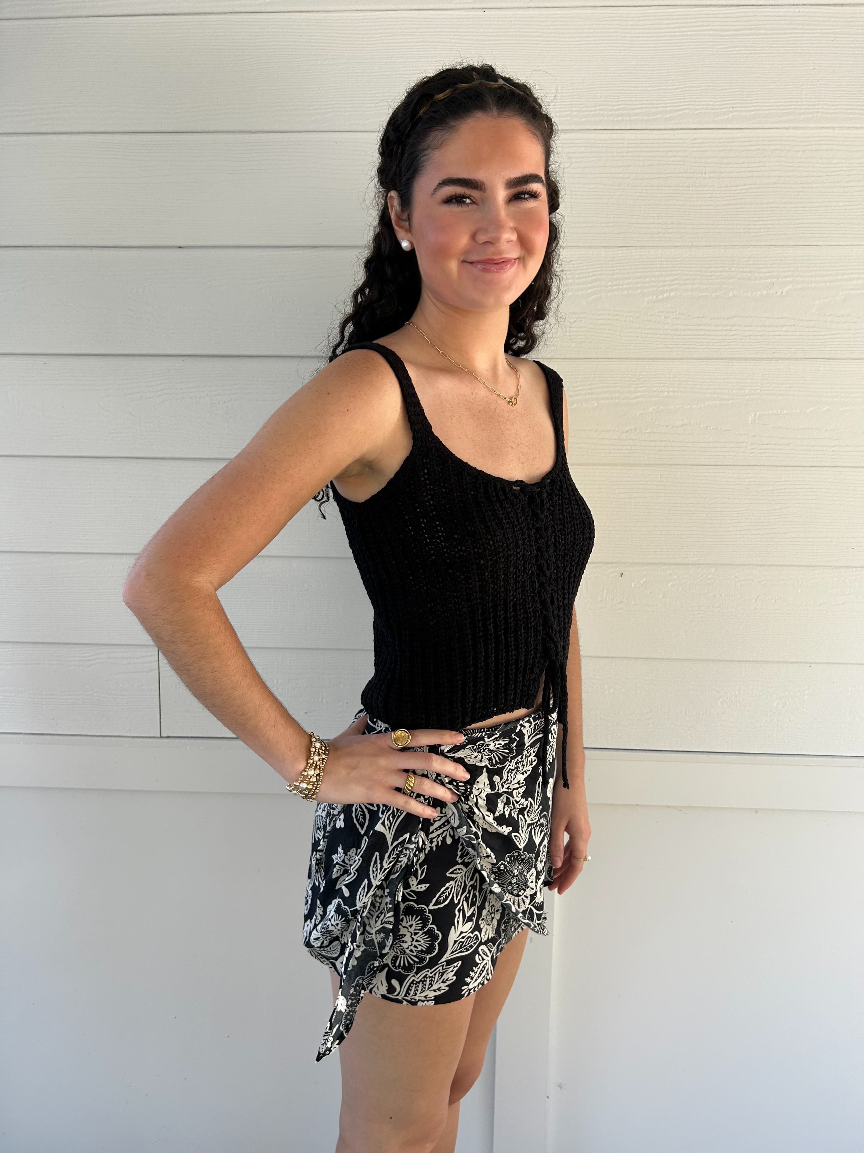 woman wearing a black knit tank top against a white backdrop