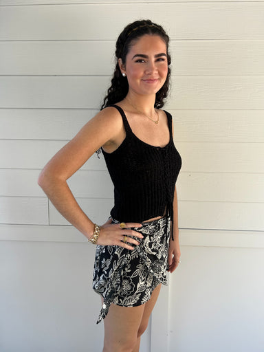 woman wearing a black knit tank top against a white backdrop