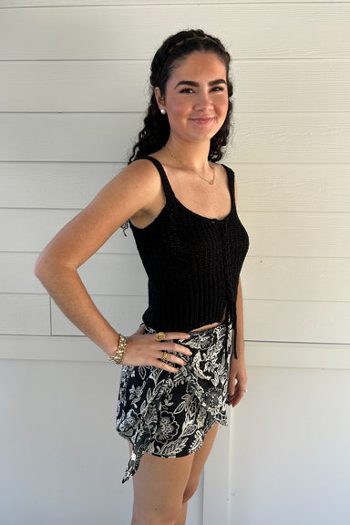 woman wearing a black knit tank top against a white backdrop