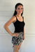 woman wearing a black knit tank top against a white backdrop