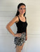 woman wearing a black knit tank top against a white backdrop