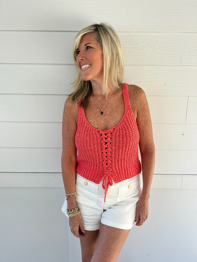 woman wearing coral sweater tank op against white background