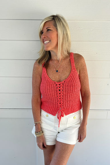 woman wearing coral sweater tank op against white background
