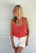 woman wearing coral sweater tank op against white background