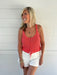 woman wearing coral sweater tank op against white background