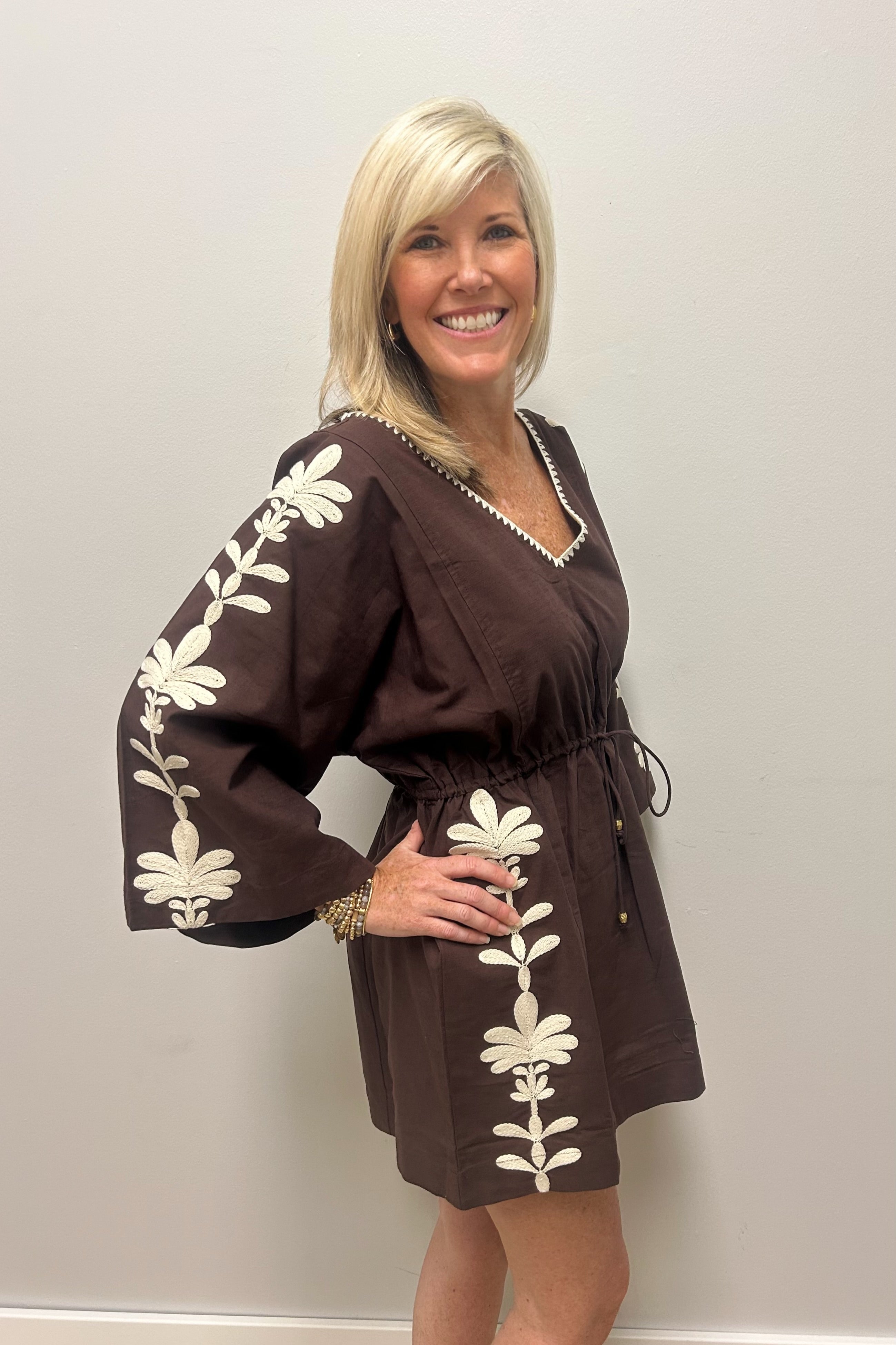 Woman wearing brown with cream detail dress against white background