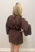 Woman wearing brown with cream detail dress against white background