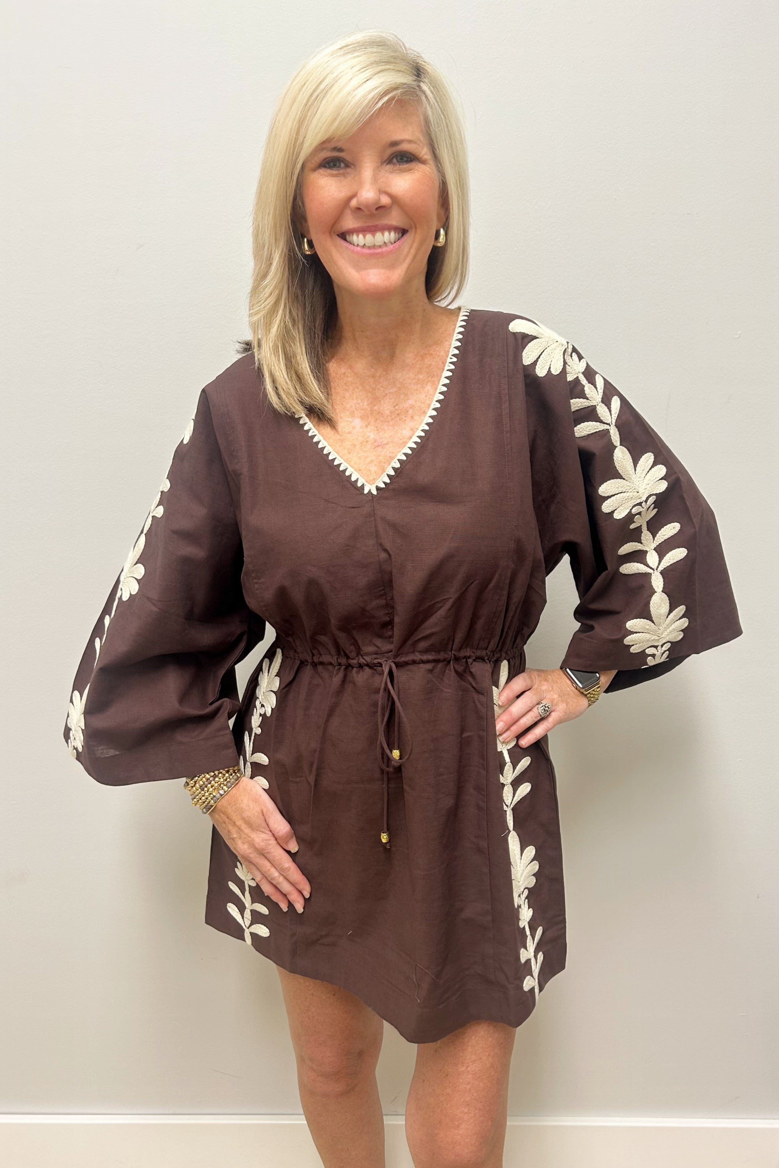 Woman wearing brown with cream detail dress against white background