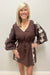 Woman wearing brown with cream detail dress against white background