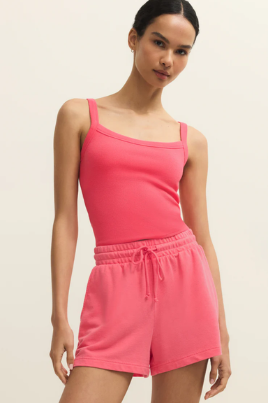 Woman wearing a pink tank top and shorts set on a beige background