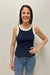 Woman wearing a navy tank top with white trim and blue jeans against a plain background