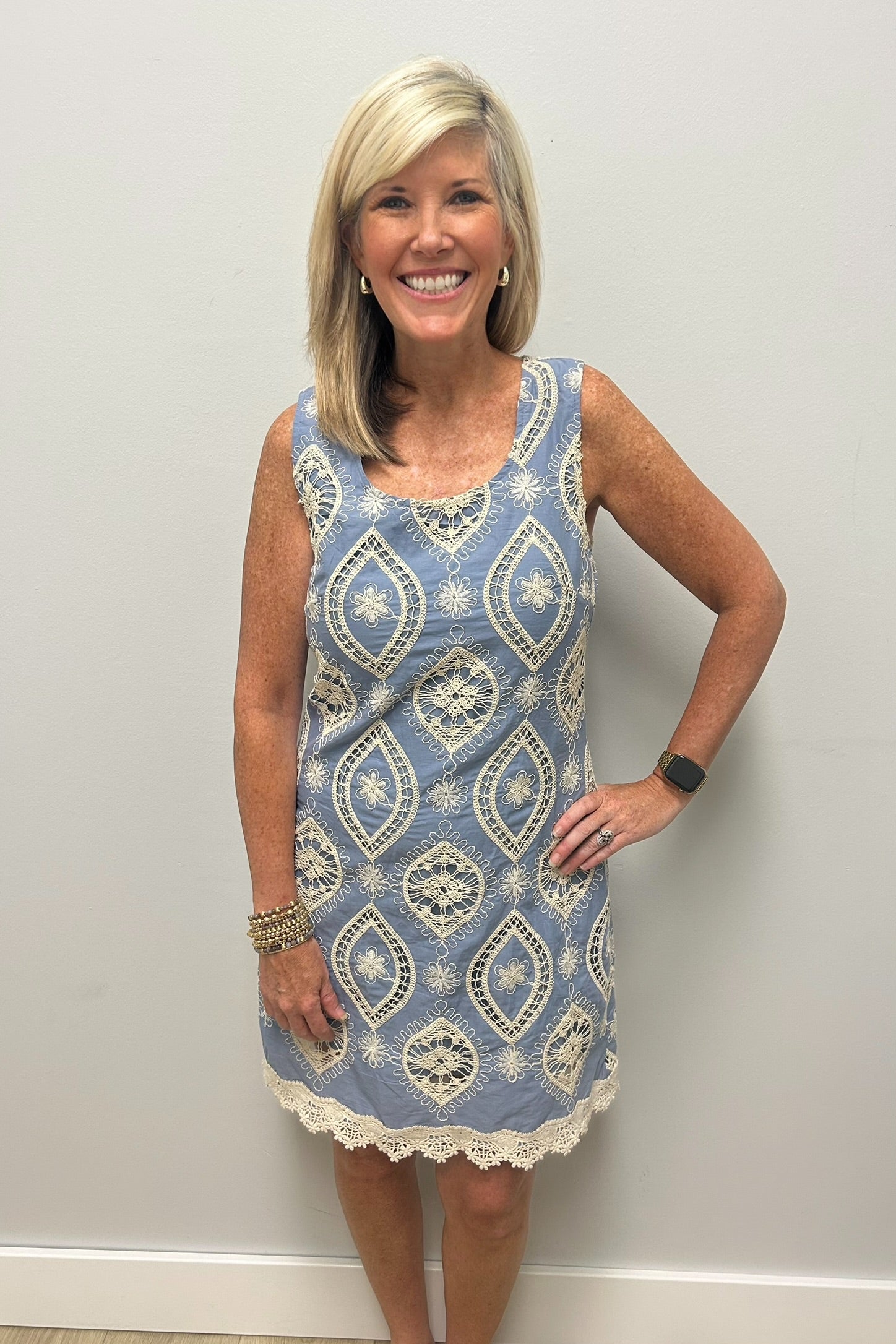 Woman wearing light blue dress with lace embroidered detail in cream