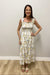 Woman wearing a floral dress standing against a plain wall.