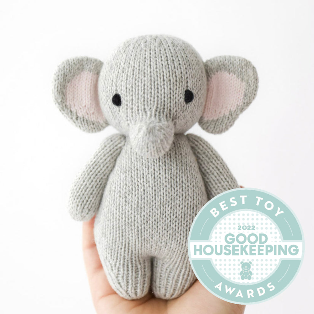 Hand-knit gray elephant stuffed animal held in an open hand to show its small size