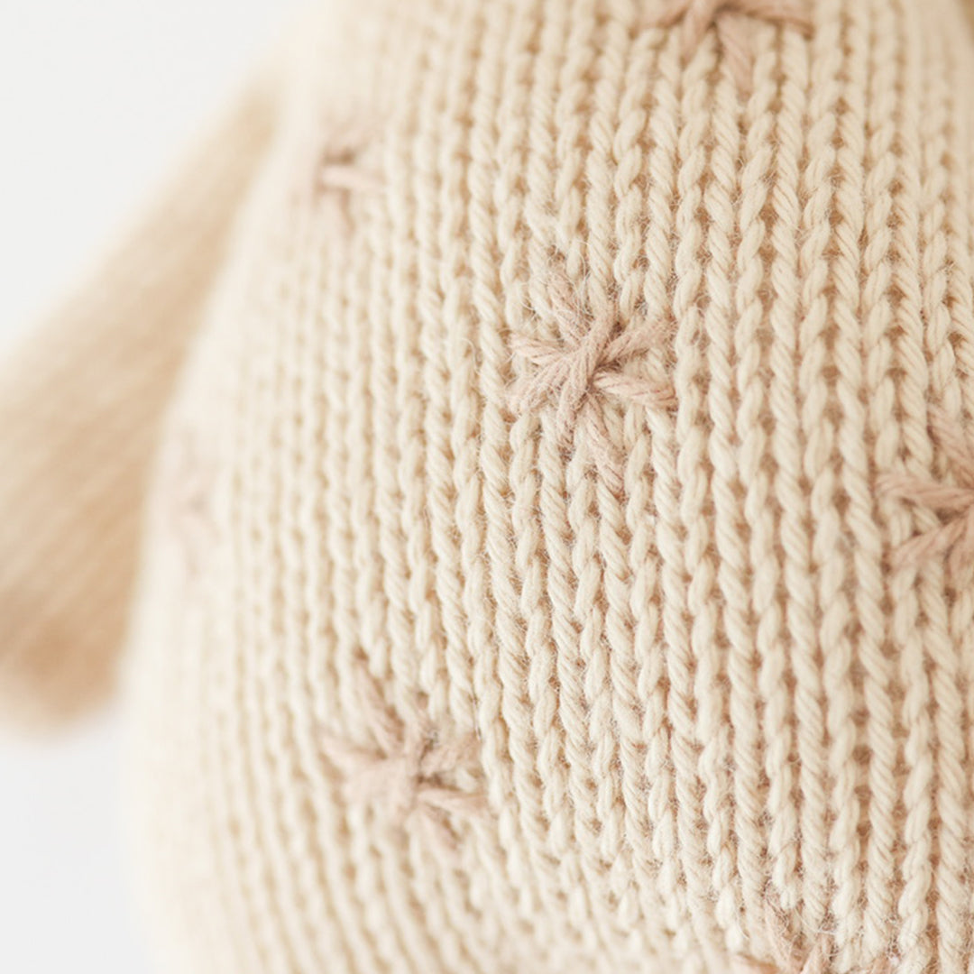 Close-up of the hand-knit stitching on a cream giraffe stuffed animal