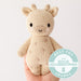 Hand-knit cream giraffe stuffed animal held in an open hand to show its small size