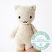 Hand-knit cream kitten stuffed animal held in an open hand to show its small size