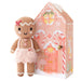 Small hand-knit gingerbread girl doll in a pink dress beside her gingerbread house box